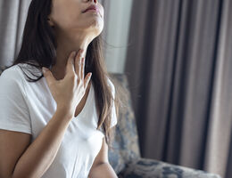  A woman feels her throat with her hand