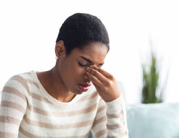  A woman pinches the bridge of her nose