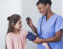 A healthcare provider measures a child’s blood pressure.