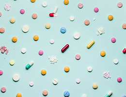 Various pills and capsules, whole and crushed, laid out in a grid. 