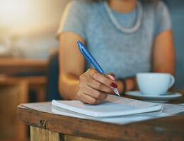 A woman writes in a notebook.